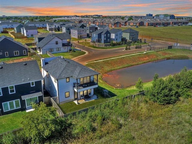 aerial view at dusk featuring a water view