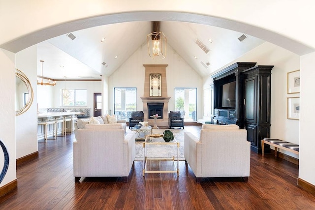 living room with a healthy amount of sunlight, high vaulted ceiling, a chandelier, and dark hardwood / wood-style floors