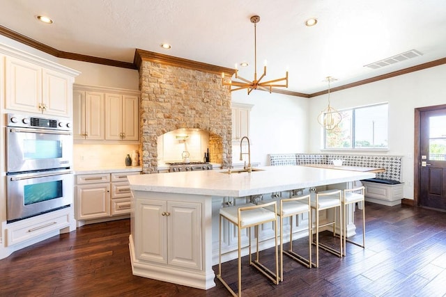 kitchen with dark hardwood / wood-style flooring, hanging light fixtures, stainless steel double oven, and sink