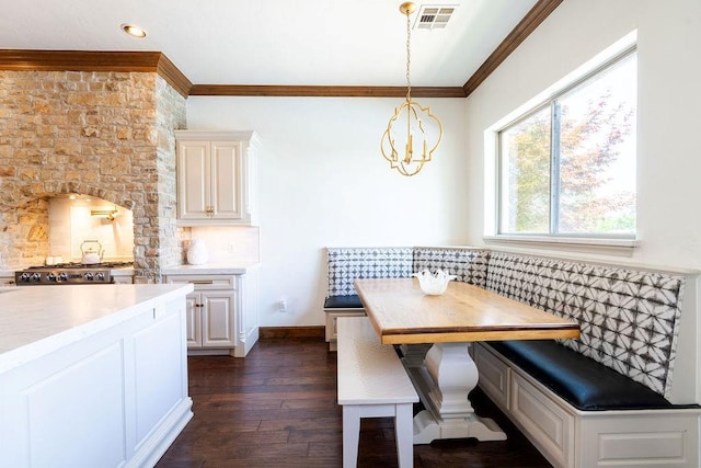 dining space featuring dark hardwood / wood-style flooring, breakfast area, an inviting chandelier, and crown molding