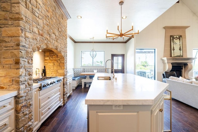 kitchen featuring pendant lighting, stainless steel gas stovetop, dark wood-type flooring, sink, and an island with sink