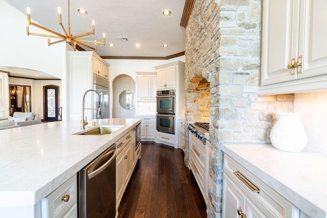 kitchen featuring light stone countertops, sink, dark hardwood / wood-style floors, a chandelier, and appliances with stainless steel finishes