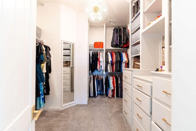 walk in closet featuring a chandelier and light colored carpet