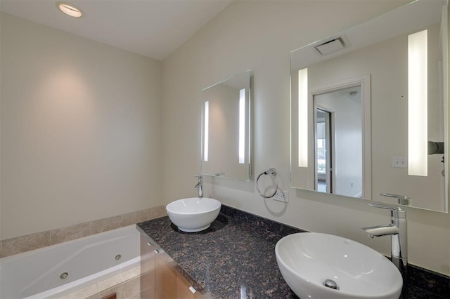 bathroom featuring tiled bath and vanity