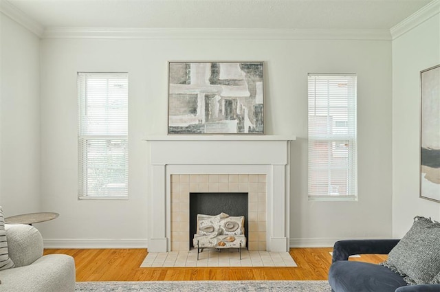 living room featuring hardwood / wood-style floors, crown molding, and a tile fireplace