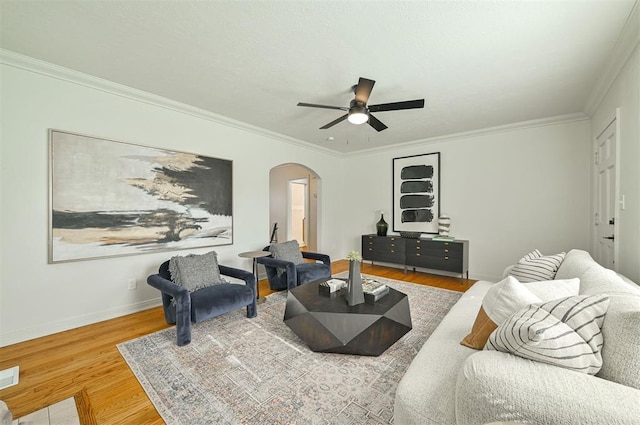 living room featuring ceiling fan, wood-type flooring, and ornamental molding