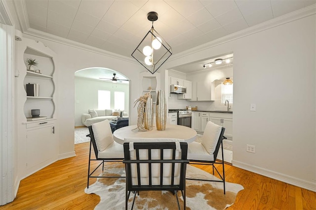 dining room featuring ceiling fan, sink, light wood-type flooring, and crown molding