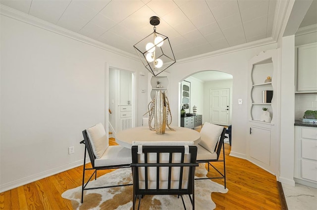 dining space featuring built in shelves, light hardwood / wood-style floors, and ornamental molding