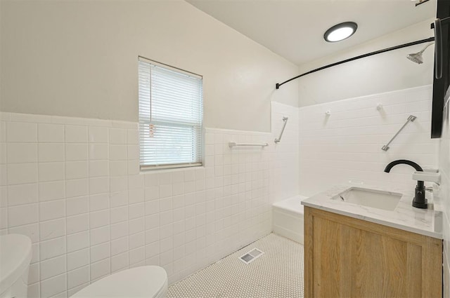 bathroom with tile patterned floors, vanity, toilet, and tile walls