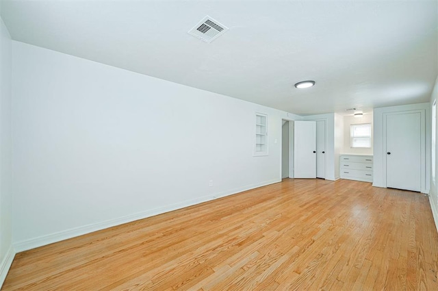 spare room with built in features and light hardwood / wood-style flooring