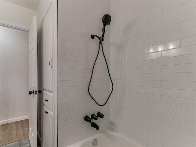 bathroom with hardwood / wood-style floors and tiled shower / bath combo