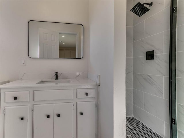 bathroom featuring a tile shower, vanity, and toilet