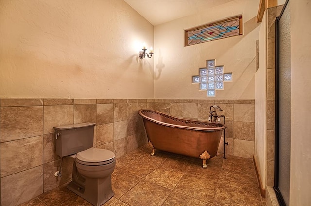 bathroom featuring toilet, a tub, and tile walls