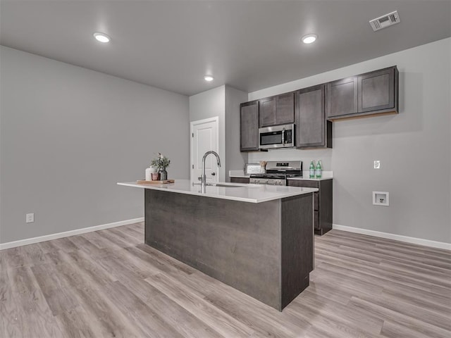 kitchen with sink, stainless steel appliances, light hardwood / wood-style flooring, a center island with sink, and dark brown cabinets