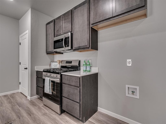 kitchen with appliances with stainless steel finishes, light hardwood / wood-style floors, and dark brown cabinets