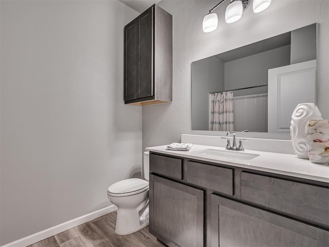 bathroom with hardwood / wood-style floors, vanity, toilet, and curtained shower