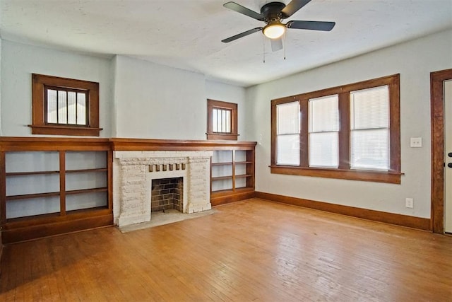 unfurnished living room featuring ceiling fan, light hardwood / wood-style floors, built in shelves, and a brick fireplace