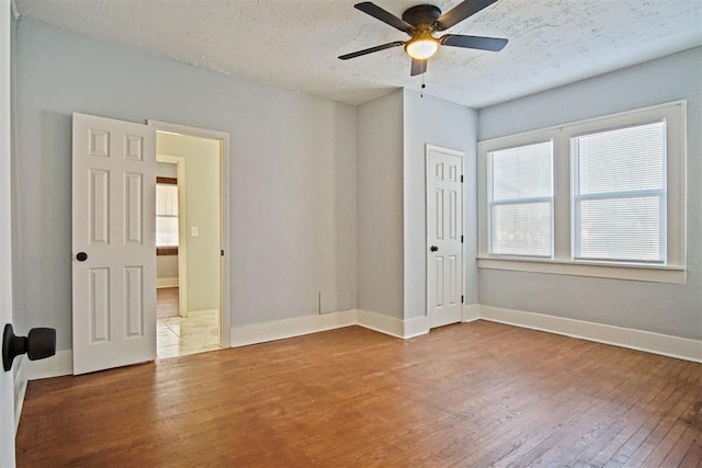 unfurnished room with hardwood / wood-style floors, ceiling fan, and a textured ceiling