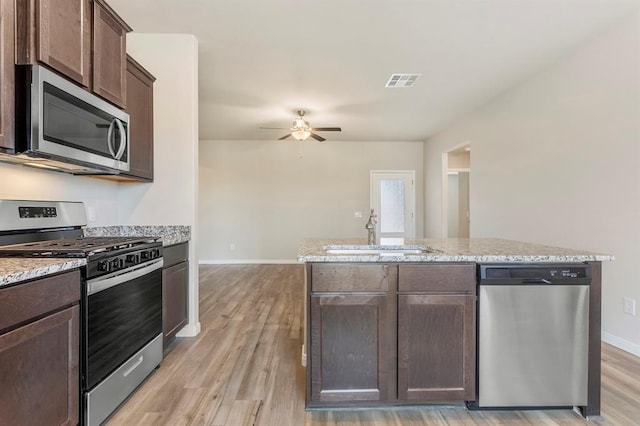 kitchen with dark brown cabinetry, light stone countertops, ceiling fan, sink, and stainless steel appliances