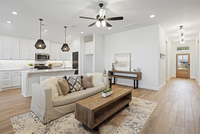 living room with ceiling fan, light hardwood / wood-style flooring, and sink