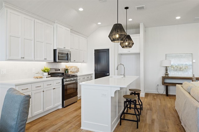 kitchen featuring backsplash, sink, an island with sink, appliances with stainless steel finishes, and white cabinetry