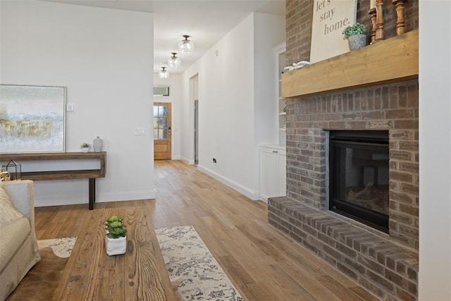 living room with light wood-type flooring and a brick fireplace