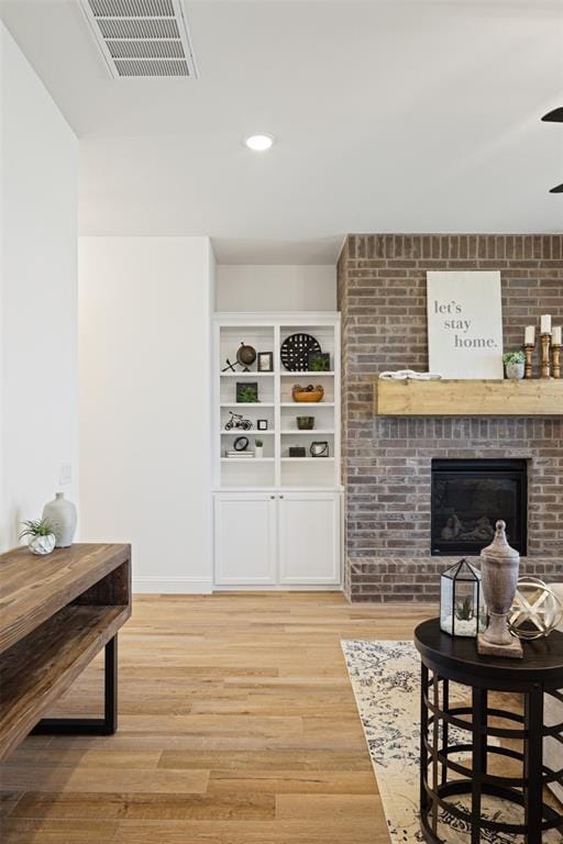 living room featuring a fireplace, light hardwood / wood-style flooring, and built in features