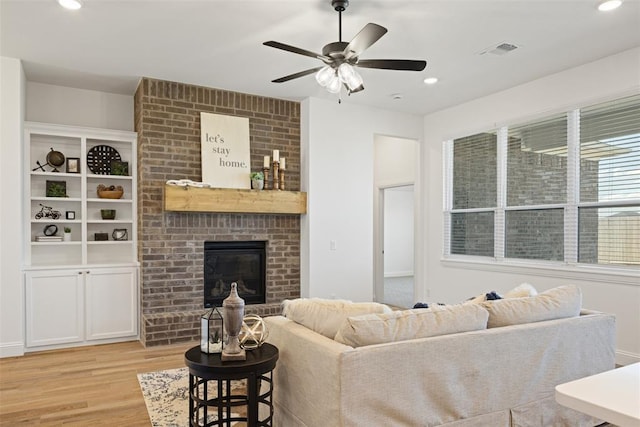 living room featuring ceiling fan, light hardwood / wood-style flooring, and a brick fireplace