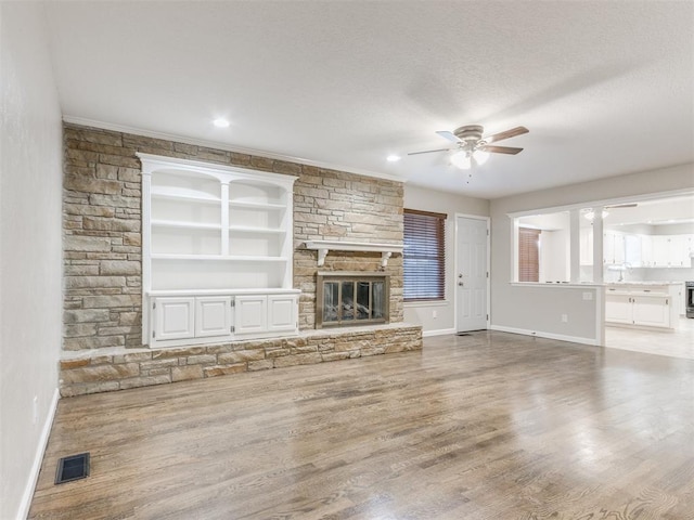 unfurnished living room with a fireplace, ceiling fan, and light wood-type flooring