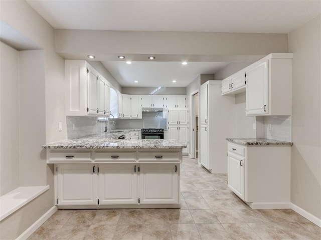 kitchen with sink, white cabinetry, light stone counters, kitchen peninsula, and decorative backsplash