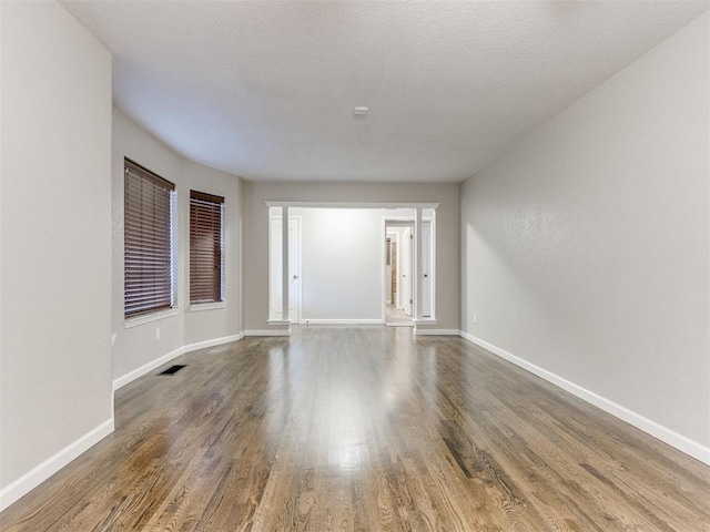 unfurnished room featuring dark wood-type flooring and a textured ceiling