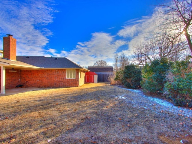 view of side of home with a yard and a storage shed