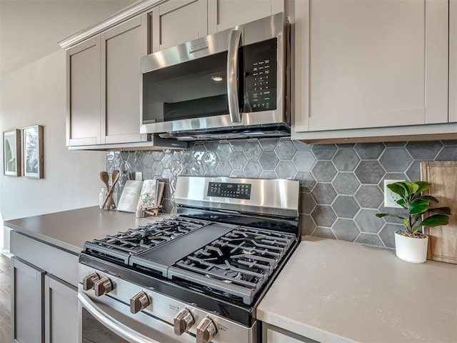 kitchen featuring decorative backsplash, stainless steel appliances, and gray cabinets