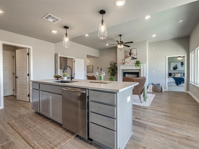 kitchen with sink, stainless steel dishwasher, an island with sink, pendant lighting, and gray cabinets