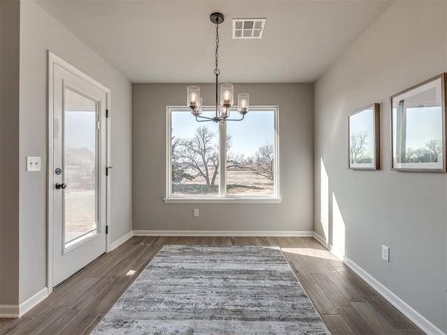 unfurnished dining area with a chandelier and dark wood-type flooring