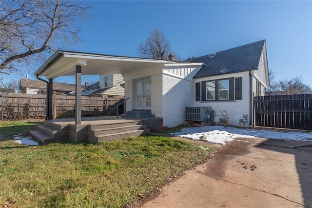 view of front of home with central air condition unit, french doors, and a front lawn