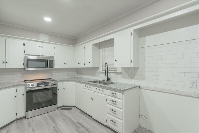 kitchen with sink, stainless steel appliances, white cabinets, and decorative backsplash