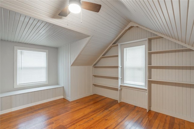 additional living space featuring dark wood-type flooring, vaulted ceiling, and plenty of natural light