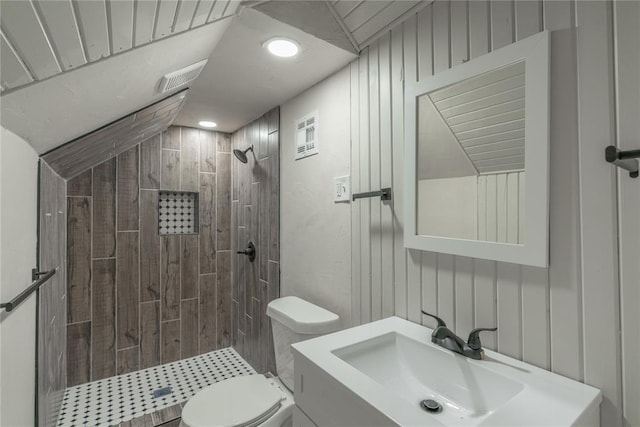 bathroom featuring tiled shower, lofted ceiling, vanity, and toilet