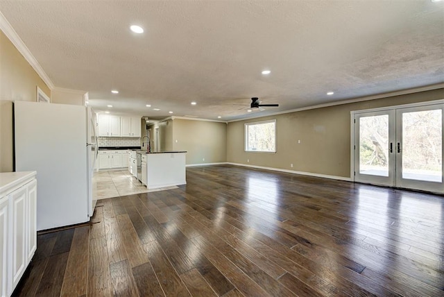 unfurnished living room with french doors, ornamental molding, ceiling fan, sink, and dark hardwood / wood-style floors