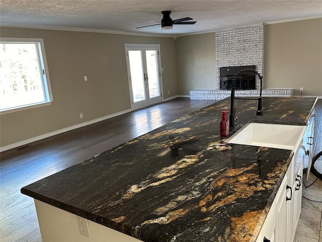 kitchen with french doors, white cabinets, crown molding, sink, and a textured ceiling