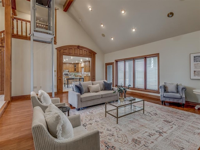 living room with beamed ceiling, high vaulted ceiling, and light wood-type flooring