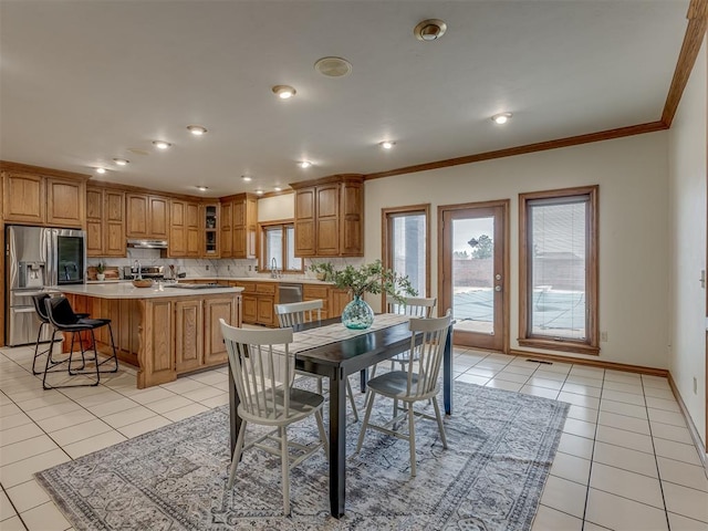 dining space featuring light tile patterned flooring, ornamental molding, and sink