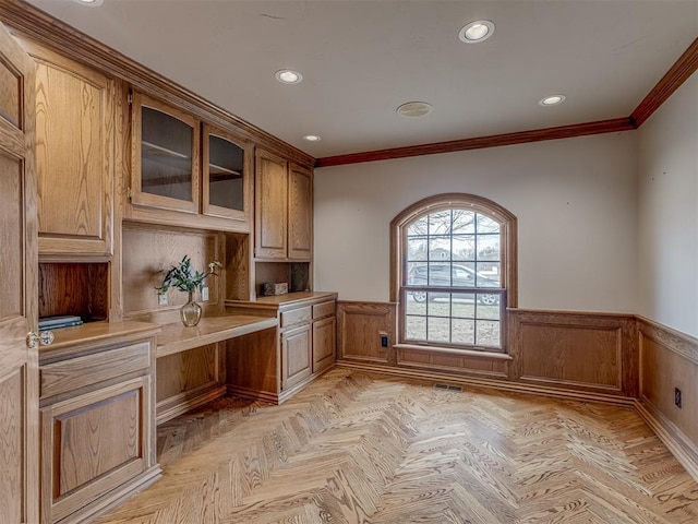 interior space featuring crown molding, built in desk, and light parquet floors