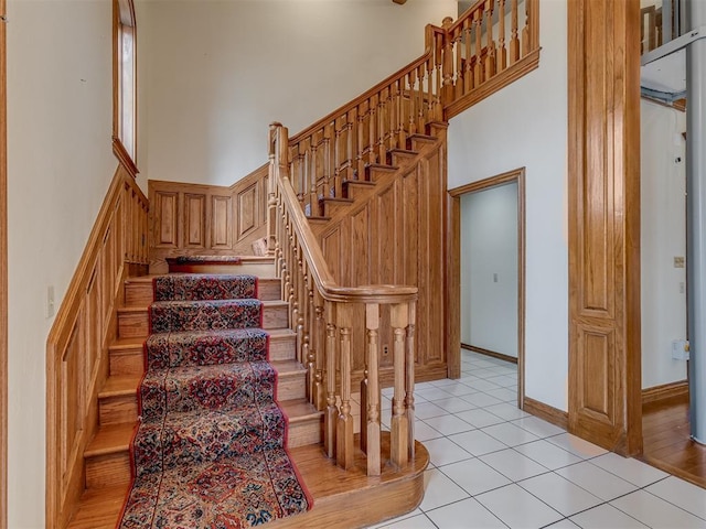 stairs featuring a towering ceiling and tile patterned floors