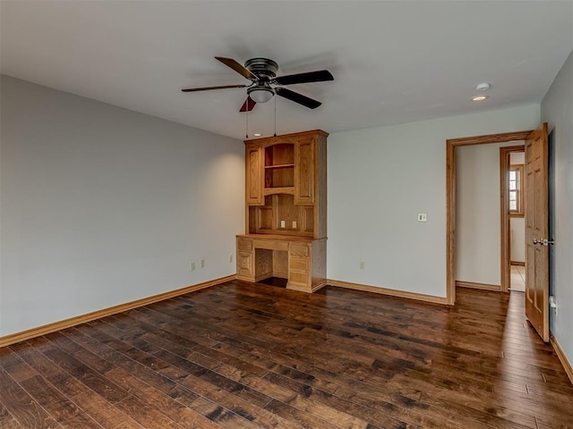 unfurnished living room with dark wood-type flooring, built in desk, and ceiling fan