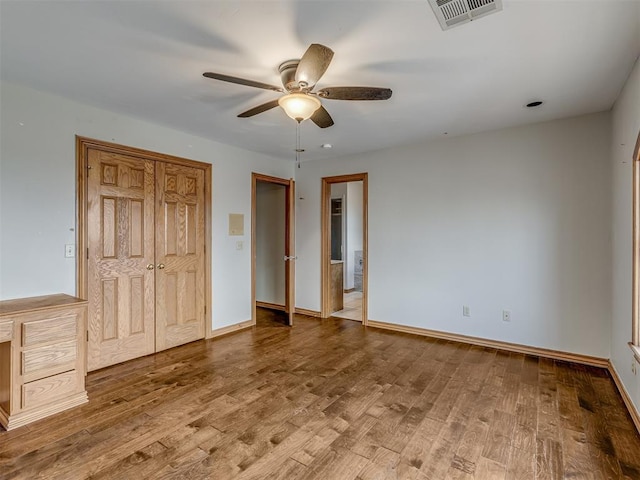 unfurnished bedroom with connected bathroom, hardwood / wood-style floors, ceiling fan, and a closet