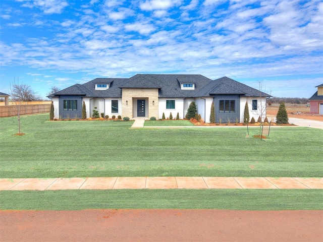 view of front facade featuring a shingled roof, a front yard, and fence