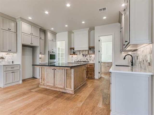 kitchen with recessed lighting, visible vents, a sink, and light wood finished floors