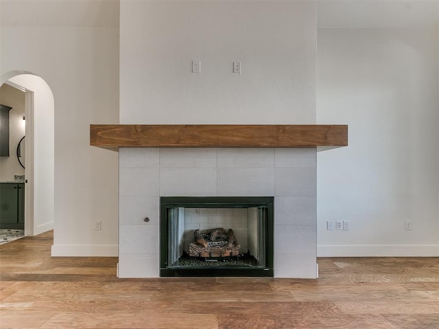 details featuring a tiled fireplace, wood finished floors, and baseboards